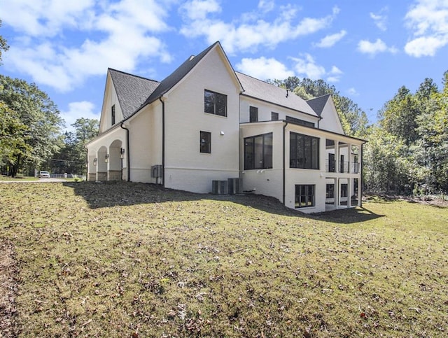 rear view of property with a sunroom, a yard, and central air condition unit