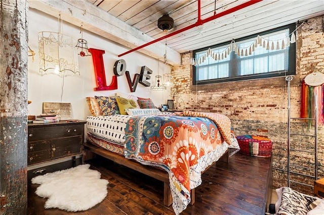 bedroom featuring hardwood / wood-style floors and brick wall