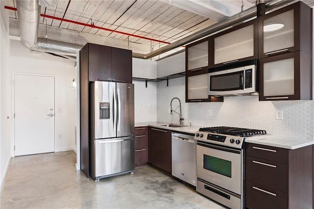 kitchen with sink, stainless steel appliances, dark brown cabinets, and light stone counters