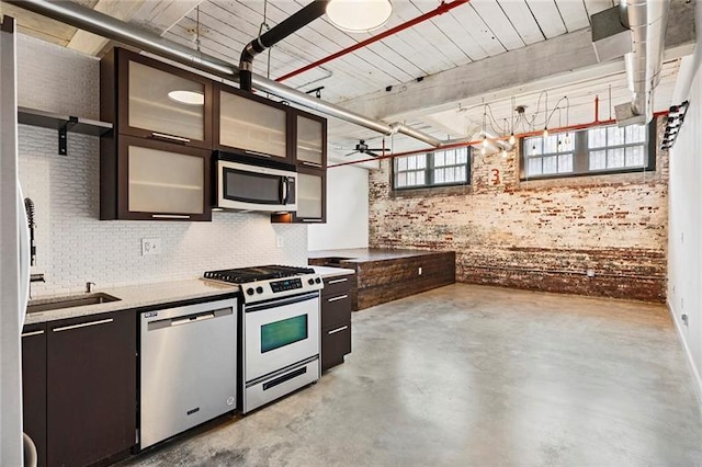 kitchen featuring brick wall, dark brown cabinetry, sink, and appliances with stainless steel finishes