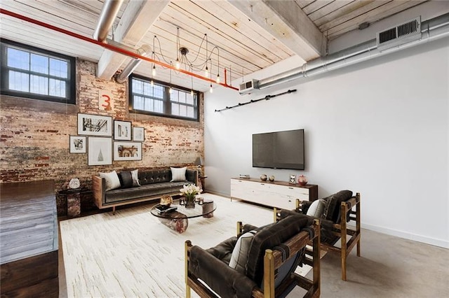 living room featuring brick wall, concrete floors, and beam ceiling