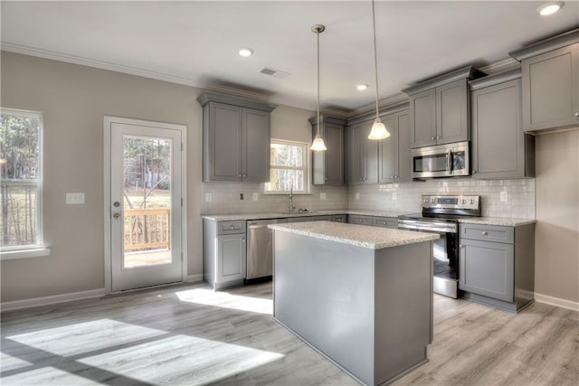 kitchen featuring appliances with stainless steel finishes, gray cabinetry, a sink, light wood-style flooring, and crown molding
