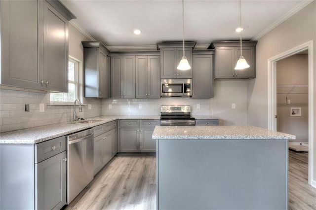kitchen featuring stainless steel appliances, gray cabinetry, crown molding, a sink, and light wood-style flooring