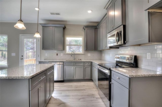 kitchen featuring stainless steel appliances, gray cabinetry, a sink, crown molding, and decorative backsplash