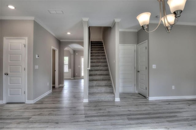 foyer entrance featuring arched walkways, baseboards, recessed lighting, wood finished floors, and ornamental molding