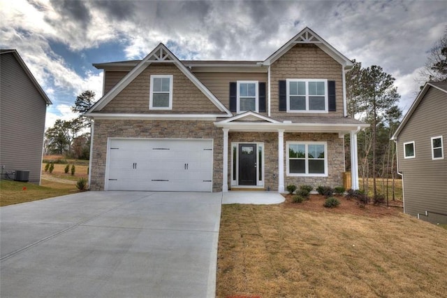 craftsman house featuring stone siding, an attached garage, a front lawn, and concrete driveway