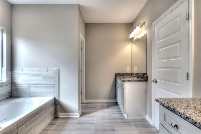 full bathroom with vanity, baseboards, a relaxing tiled tub, and tile patterned floors