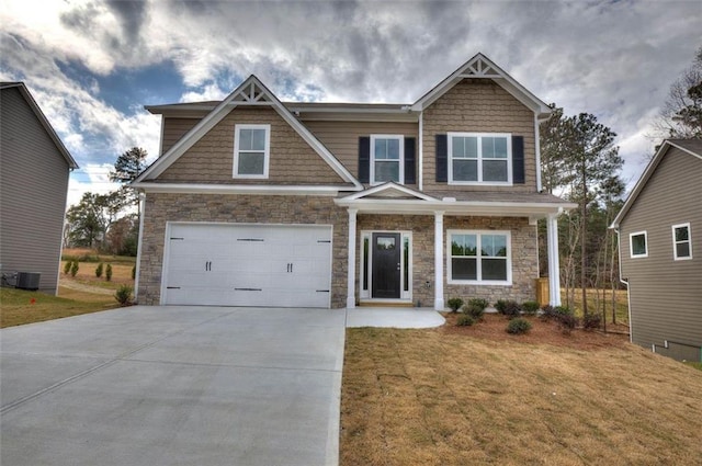 craftsman-style home with stone siding, an attached garage, cooling unit, concrete driveway, and a front yard