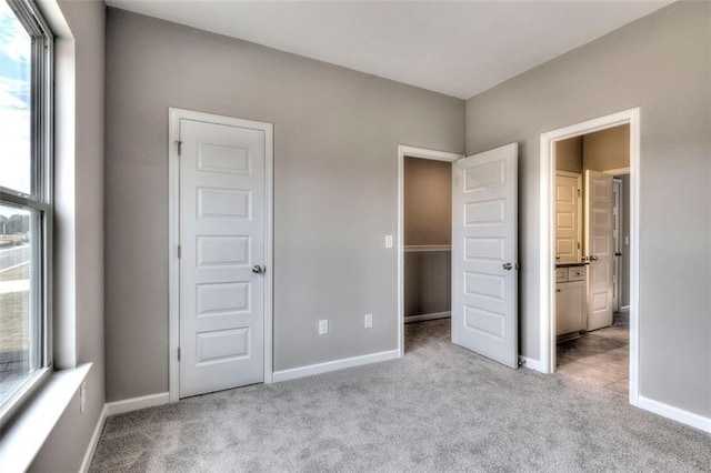 unfurnished bedroom featuring light carpet, baseboards, and connected bathroom