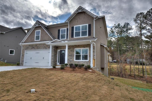 craftsman house with driveway, an attached garage, a front yard, and stone siding