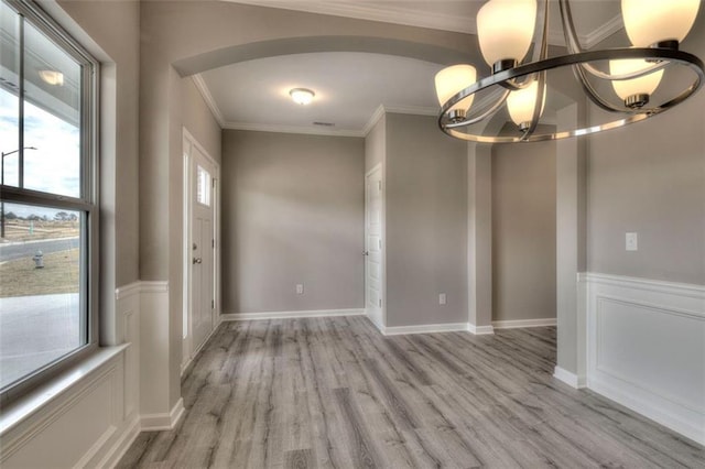 empty room featuring wood finished floors, a chandelier, and crown molding