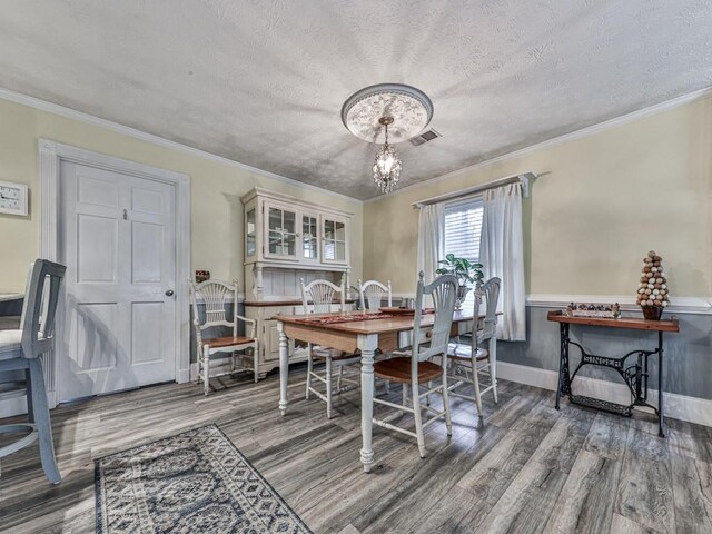 dining room featuring crown molding, a notable chandelier, hardwood / wood-style flooring, and a textured ceiling