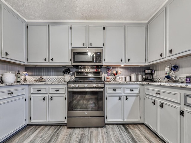 kitchen featuring white cabinets, appliances with stainless steel finishes, a textured ceiling, and light hardwood / wood-style floors