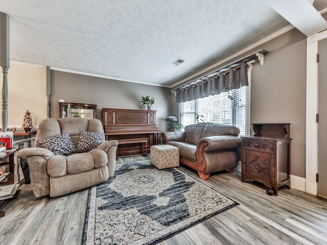 living room with ornamental molding, light hardwood / wood-style floors, and a textured ceiling