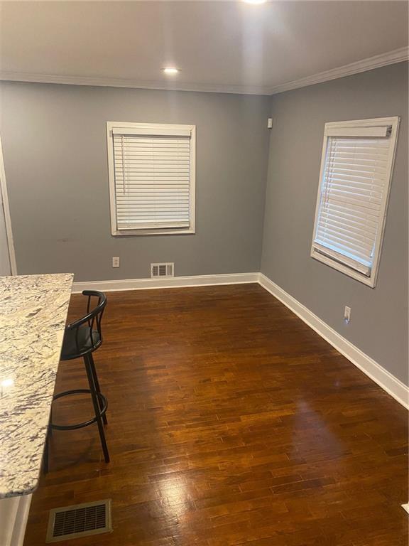 unfurnished dining area with ornamental molding and dark wood-type flooring