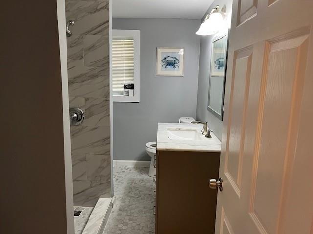 bathroom featuring vanity, toilet, and tiled shower