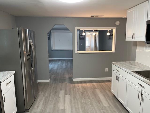 kitchen with light stone countertops, light hardwood / wood-style flooring, white cabinets, and stainless steel appliances