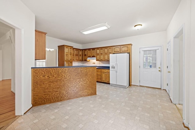 kitchen with light hardwood / wood-style floors, white fridge with ice dispenser, and kitchen peninsula