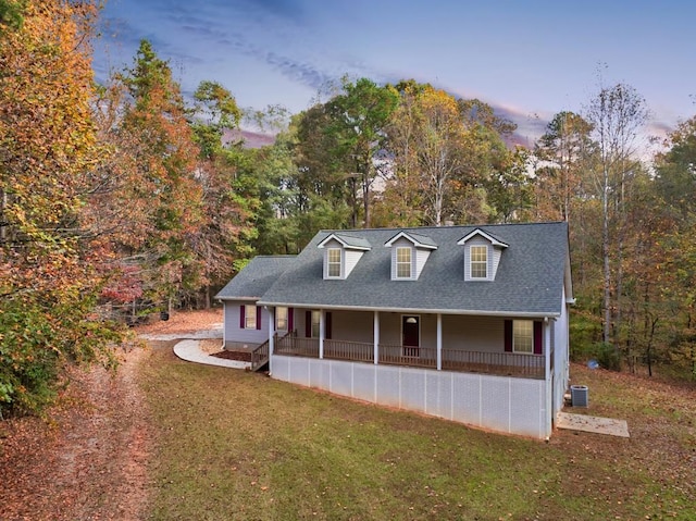 cape cod home featuring central AC unit, a porch, and a lawn