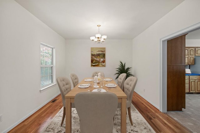 dining area featuring hardwood / wood-style floors and an inviting chandelier