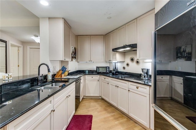 kitchen featuring dark stone counters, white cabinets, black appliances, sink, and light hardwood / wood-style flooring