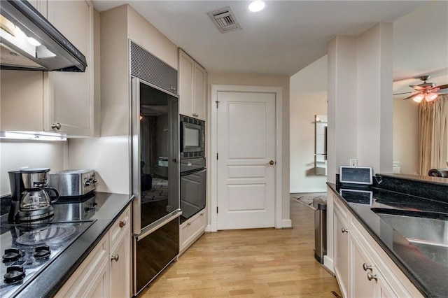 kitchen with black appliances, white cabinets, sink, ceiling fan, and light wood-type flooring