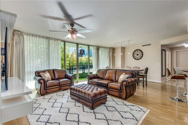 living room featuring rail lighting, a wall of windows, light hardwood / wood-style flooring, and ceiling fan