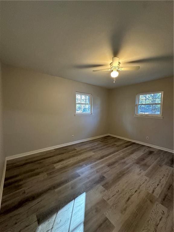 spare room featuring baseboards, dark wood finished floors, and a ceiling fan