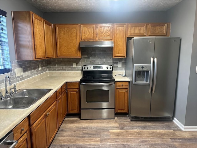 5768 Windgate Ln, Lithonia, GA 30058 - kitchen with stainless steel appliances, under cabinet range hood, wood finished floors, brown cabinets, and light countertops