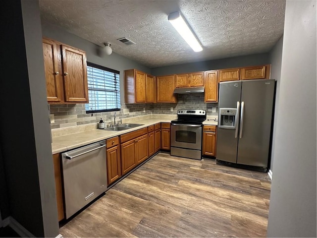 5768 Windgate Ln, Lithonia, GA 30058 - kitchen featuring appliances with stainless steel finishes, under cabinet range hood, wood finished floors, light countertops, and a textured ceiling