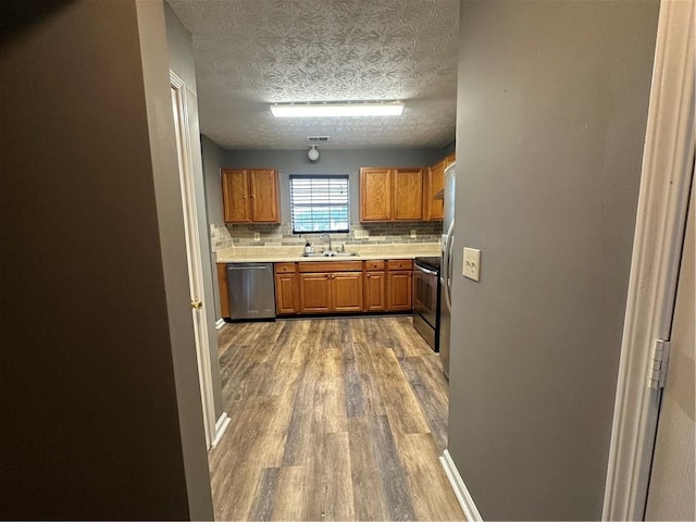 5768 Windgate Ln, Lithonia, GA 30058 - kitchen featuring stainless steel dishwasher, wood finished floors, light countertops, tasteful backsplash, and a textured ceiling