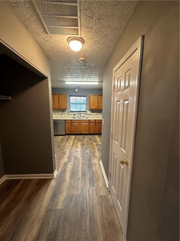 5768 Windgate Ln, Lithonia, GA 30058 - kitchen featuring brown cabinets, stainless steel dishwasher, dark wood-style floors, light countertops, and a textured ceiling