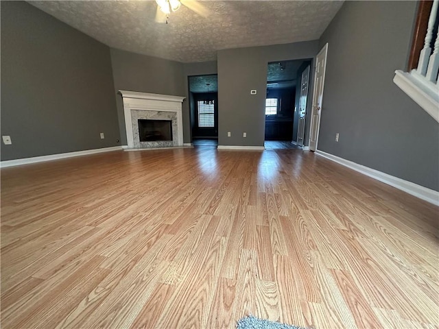5768 Windgate Ln, Lithonia, GA 30058 - unfurnished living room with wood finished floors, a textured ceiling, a high end fireplace, and a ceiling fan