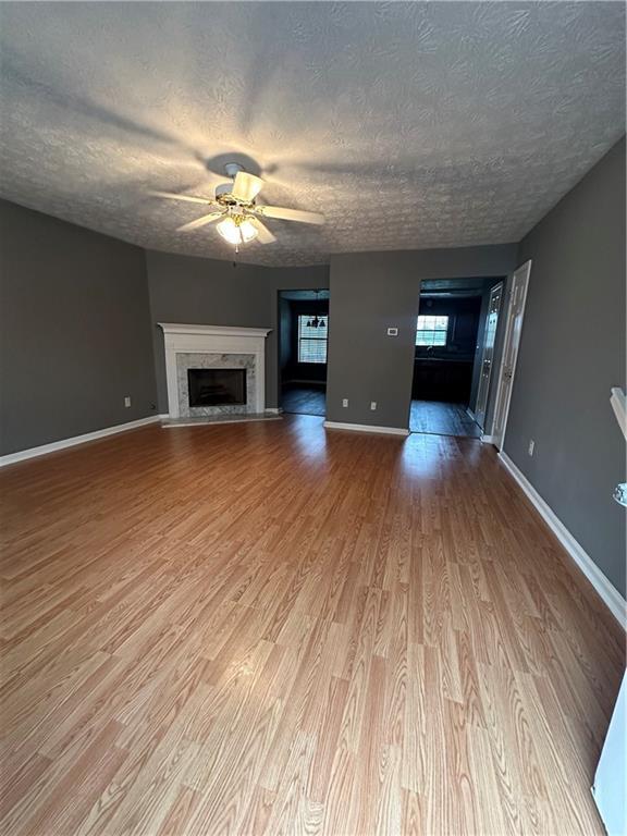 5768 Windgate Ln, Lithonia, GA 30058 - unfurnished living room with a premium fireplace, a ceiling fan, wood finished floors, and a textured ceiling