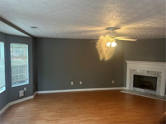 5768 Windgate Ln, Lithonia, GA 30058 - unfurnished living room with wood finished floors, healthy amount of natural light, a ceiling fan, a textured ceiling, and a high end fireplace
