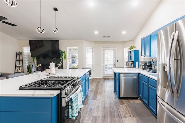 kitchen with light wood finished floors, visible vents, appliances with stainless steel finishes, open floor plan, and blue cabinets