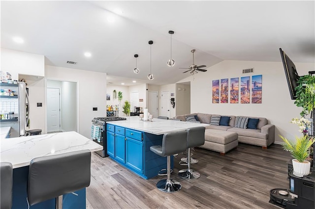 kitchen featuring visible vents, open floor plan, blue cabinets, stainless steel appliances, and light wood-style floors