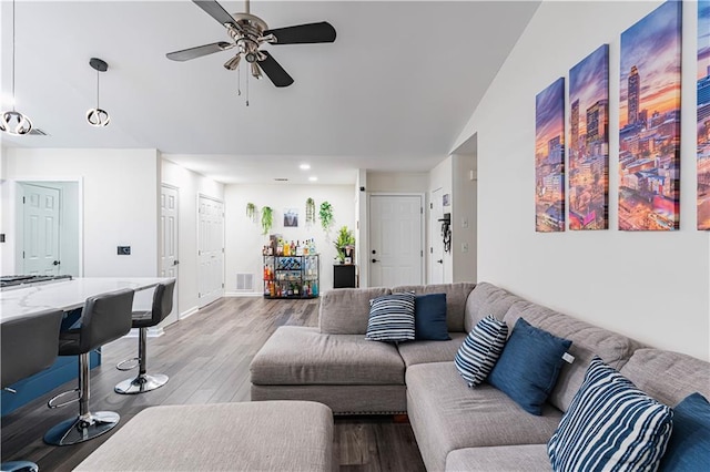 living room featuring baseboards, visible vents, lofted ceiling, ceiling fan, and wood finished floors