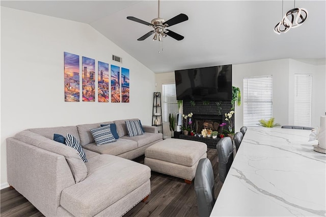 living room featuring visible vents, lofted ceiling, dark wood-style floors, ceiling fan, and a brick fireplace