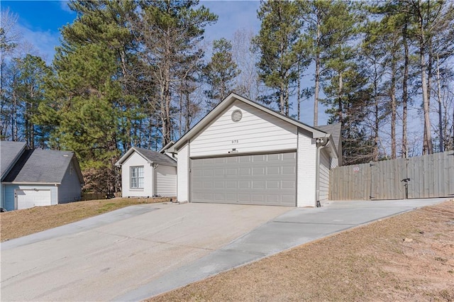 garage featuring fence and concrete driveway