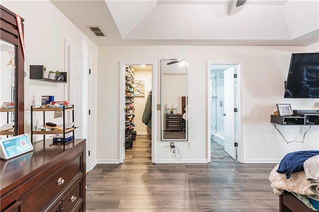 interior space featuring baseboards, visible vents, connected bathroom, dark wood-style flooring, and a tray ceiling