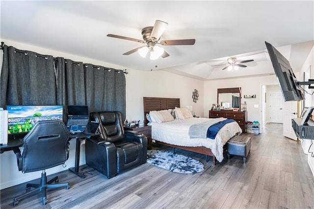 bedroom featuring ceiling fan, a raised ceiling, and wood finished floors