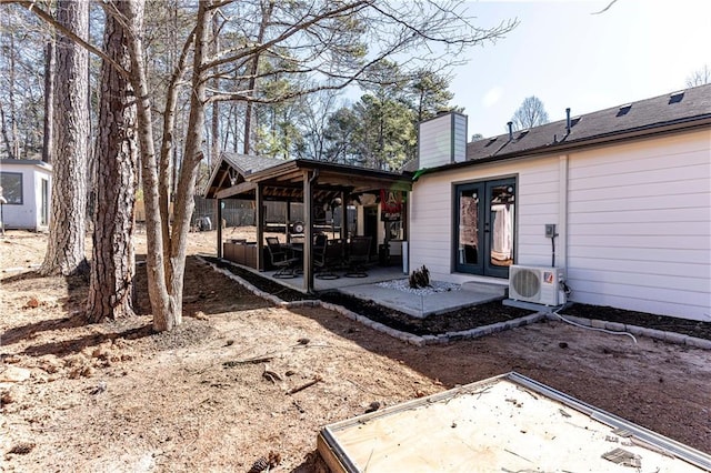 back of property with a chimney, french doors, ac unit, and a patio area