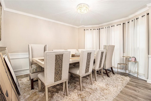 dining area with an inviting chandelier, ornamental molding, and hardwood / wood-style floors