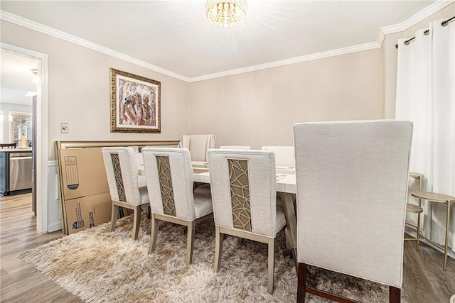 dining area with crown molding, hardwood / wood-style flooring, and an inviting chandelier