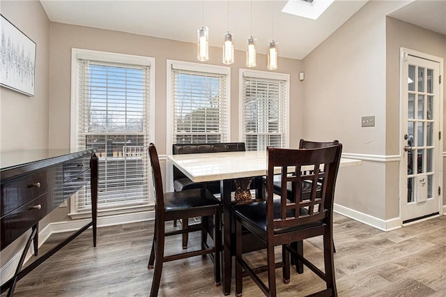 dining room featuring hardwood / wood-style floors and lofted ceiling with skylight