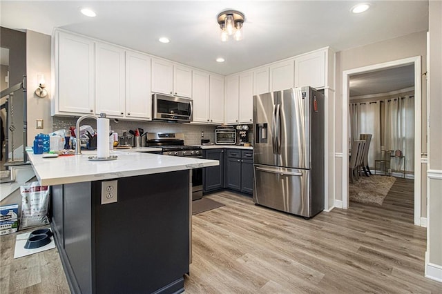 kitchen with decorative backsplash, appliances with stainless steel finishes, light hardwood / wood-style flooring, and white cabinets