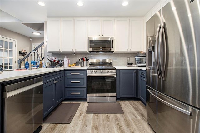 kitchen featuring white cabinetry, light hardwood / wood-style flooring, stainless steel appliances, and blue cabinets