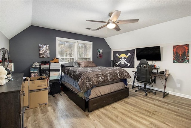 bedroom with lofted ceiling, ceiling fan, wood-type flooring, and a textured ceiling