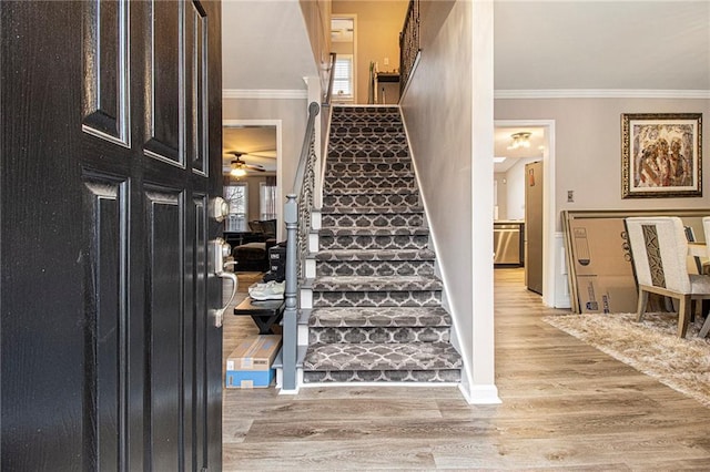 staircase with wood-type flooring and ornamental molding